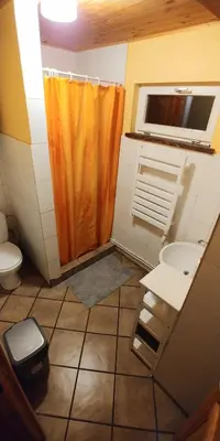 a bathroom with an orange shower curtain and a sink at Antanelio Sapnas in Pabradė
