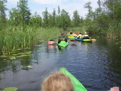 a group of people in kayaks on a river at Antanelio Sapnas in Pabradė