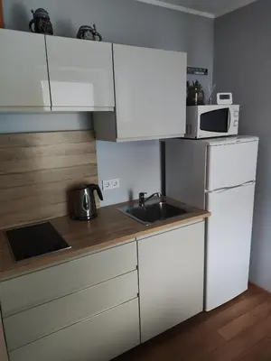 a kitchen with white cabinets and a sink and a microwave at Old Slabada Apartments in Kaunas