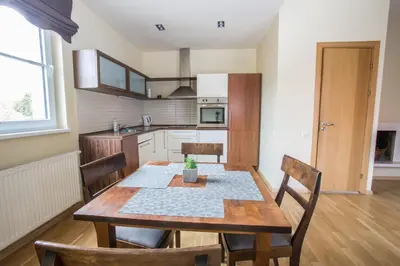 a kitchen and dining room with a wooden table and chairs at Apartments Ameda in Vilnius