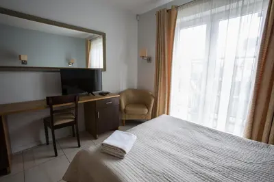 a bedroom with a bed and a desk and a mirror at Apartments Ameda in Vilnius