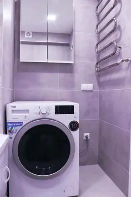 a washing machine in a bathroom with purple walls at Butas miesto centre in Panevėžys