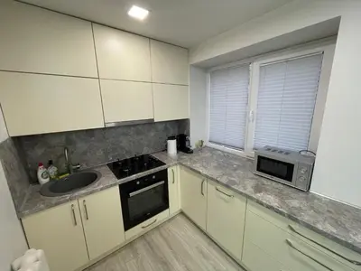 a kitchen with white cabinets and a sink and a microwave at Butas miesto centre in Panevėžys