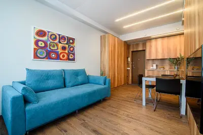 a living room with a blue couch and a kitchen at Apartment with amazing view! in Vilnius