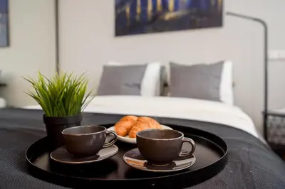 a tray with two cups and croissants on a bed at Apartment with amazing view! in Vilnius
