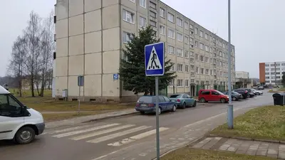 a blue sign in the middle of a street with cars at Girelės apartamentai in Kaišiadorys
