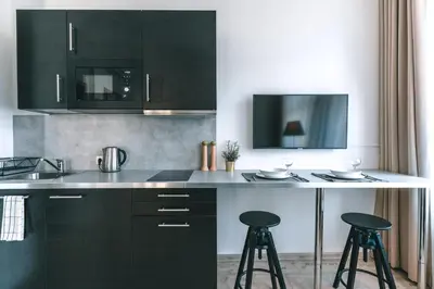 a kitchen with black cabinets and two bar stools at Brother House Kaunas in Kaunas
