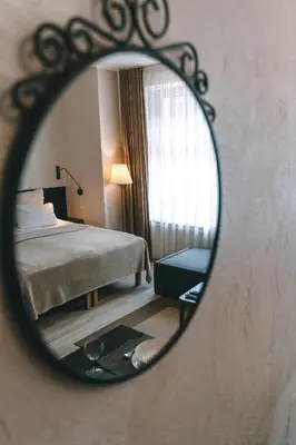a mirror reflecting a bedroom with a bed and a window at Brother House Kaunas in Kaunas