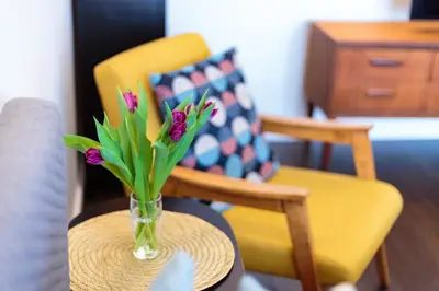 a vase of flowers on a table with a chair at Romantic apartment close to the Old Town in Vilnius