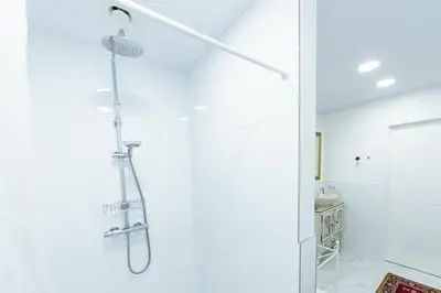 a white bathroom with a shower with a glass door at Romantic apartment close to the Old Town in Vilnius