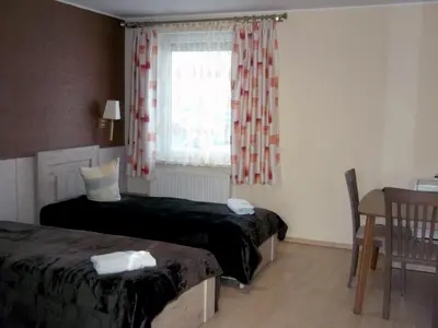 a bedroom with two beds and a window and a table at Kambarių nuoma - Rumšiškės SAURIDA in Rumšiškės