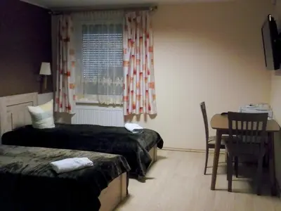 a bedroom with two beds and a table and a window at Kambarių nuoma - Rumšiškės SAURIDA in Rumšiškės