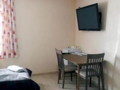 a room with a table and chairs and a tv on the wall at Kambarių nuoma - Rumšiškės SAURIDA in Rumšiškės