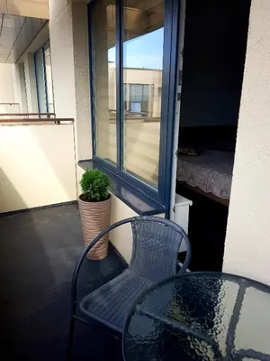 a table and a chair on a balcony with a window at Barbora apartament in Druskininkai