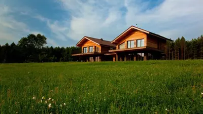 a wooden house on top of a green field at Ami Residence in Druskininkai