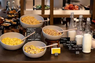 a buffet of bowls of food with wooden spoons at Hilton Garden Inn Vilnius City Centre in Vilnius
