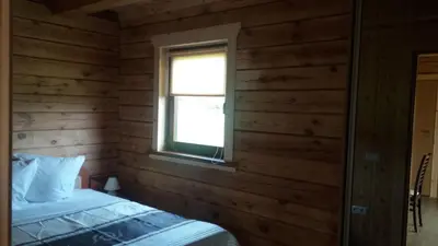 a bedroom with wooden walls and a bed with a window at Country Houses Vidų Sodyba in Utena