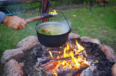 a person cooking a soup in a pot on a grill at Sodyba Latkrantė, Druskininkai in Latežeris