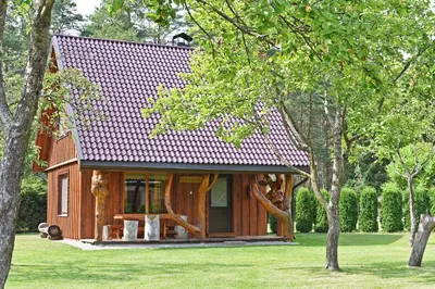 a small wooden house in a park with trees at Sodyba Latkrantė, Druskininkai in Latežeris