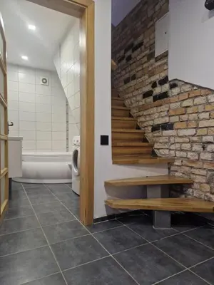a bathroom with a staircase and a brick wall at VK Duplex Apartment in Druskininkai