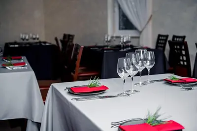 a group of tables with wine glasses and napkins at Greta in Druskininkai