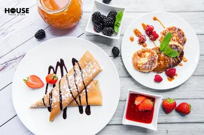 two plates of breakfast foods with fruit on a table at Greta in Druskininkai