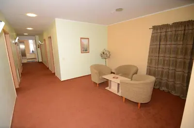 a waiting room with chairs and a table and curtains at VESK Svečių Namai in Druskininkai