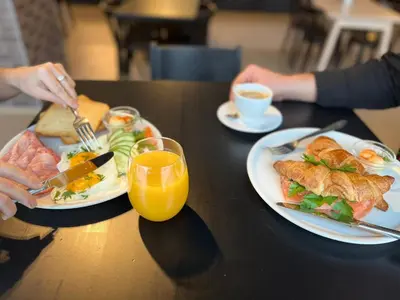 a table with two plates of food and a glass of orange juice at VESK Svečių Namai in Druskininkai