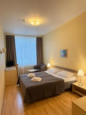 a hotel room with a bed and a chair at VESK Svečių Namai in Druskininkai