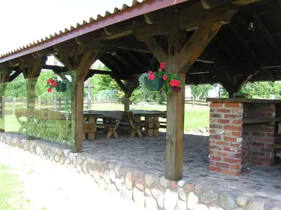 a wooden gazebo with a table and flowers at sodyba 
