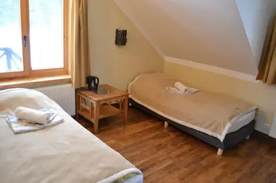 a room with two beds and a table and a window at sodyba 