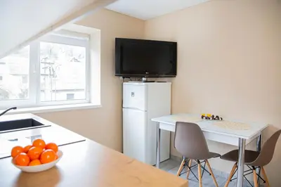 a kitchen with a white refrigerator and a table with a bowl of oranges at Chill&Go Apartment in Kaunas
