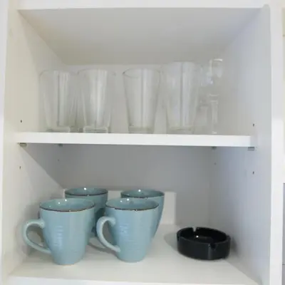 a row of glass cups sitting on a shelf at Bright 1BD Apartment in Old Town by Hostlovers in Kaunas