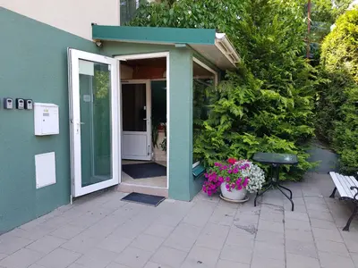 an open door of a house with flowers and a bench at EVArent Apartament Free parking in Vilnius