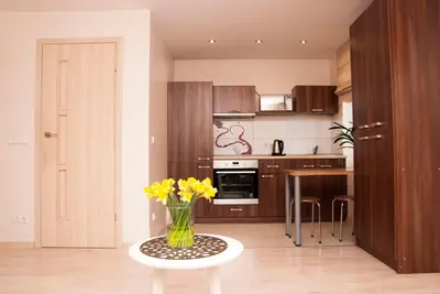 a kitchen with a vase of yellow flowers on a table at EVArent Apartament Free parking in Vilnius