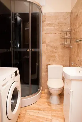 a bathroom with a washing machine and a toilet at EVArent Apartament Free parking in Vilnius