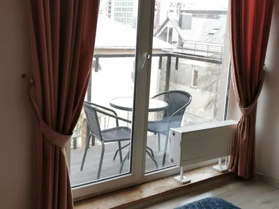 a room with a window with a table and chairs on a balcony at EVArent Apartament Free parking in Vilnius