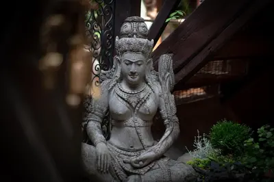 a statue of a deity sitting next to a plant at Mai Ram Yoga House in Vilnius