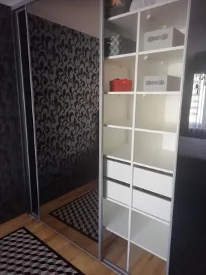 a closet with white shelves and a glass door at Justinos Apartamentai Panevėžyje in Panevėžys