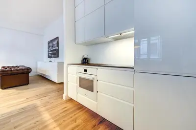 a kitchen with white cabinets and a wooden floor at Center Apartment, Vilnius, Old Town in Vilnius