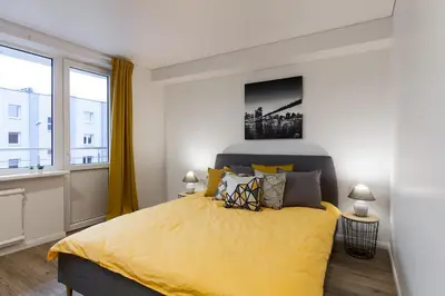 a bedroom with a large bed with yellow sheets at Pušyno apartamentai in Anykščiai