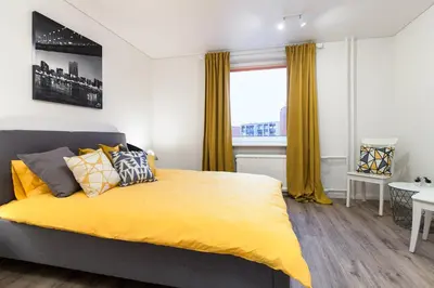 a bedroom with a bed with yellow sheets and a window at Pušyno apartamentai in Anykščiai