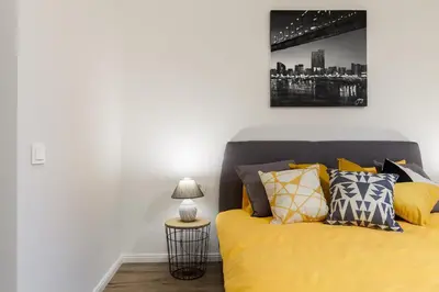 a bedroom with a bed with yellow sheets and a lamp at Pušyno apartamentai in Anykščiai