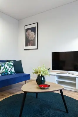 a living room with a blue couch and a coffee table at Pušyno apartamentai in Anykščiai