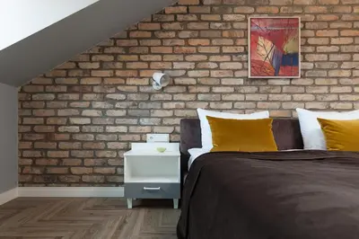 a bedroom with a brick wall and a bed with yellow pillows at Somnia Apartments in Vilnius
