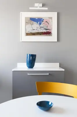 a dining room with a white table and a yellow chair at Somnia Apartments in Vilnius