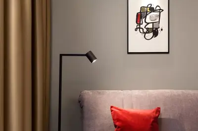 a lamp sitting next to a couch with a red pillow at Somnia Apartments in Vilnius