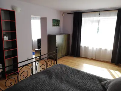 a bedroom with a bed and two large windows at Park apartment in Kaunas