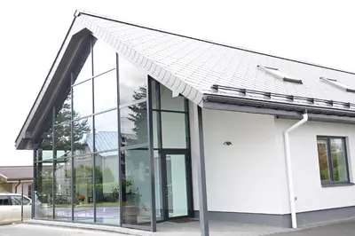 a white building with a metal roof at Lofts - Kaunas airport in Karmėlava