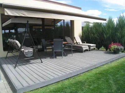 a deck with chairs and a table and an umbrella at Geras miegas in Druskininkai